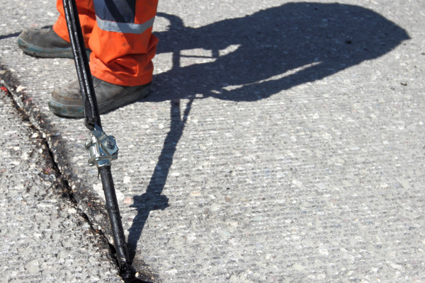 worker repairing a crack in a concrete or asphalt surface.