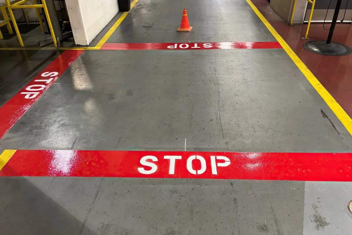 polished concrete floor in what appears to be an industrial or warehouse setting. The floor has been marked with safety lines and stop indicators.