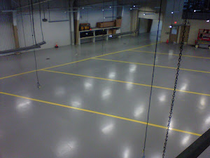 large, indoor space with a polished gray concrete floor marked with yellow lines.